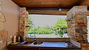 A kitchen with a stone wall, a window, and a view of greenery outside. - House 1012/3351 (Istria - Fažana), 1000m from the beach (Fažana)