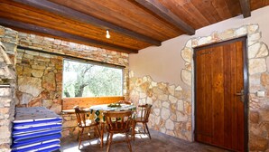 A stone-walled room with a wooden door, a window, and a table with chairs. - House 1012/3351 (Istria - Fažana), 1000m from the beach (Fažana)