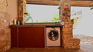 A laundry area with a washing machine, a sink, and a stone wall. - House 1012/3351 (Istria - Fažana), 1000m from the beach (Fažana)