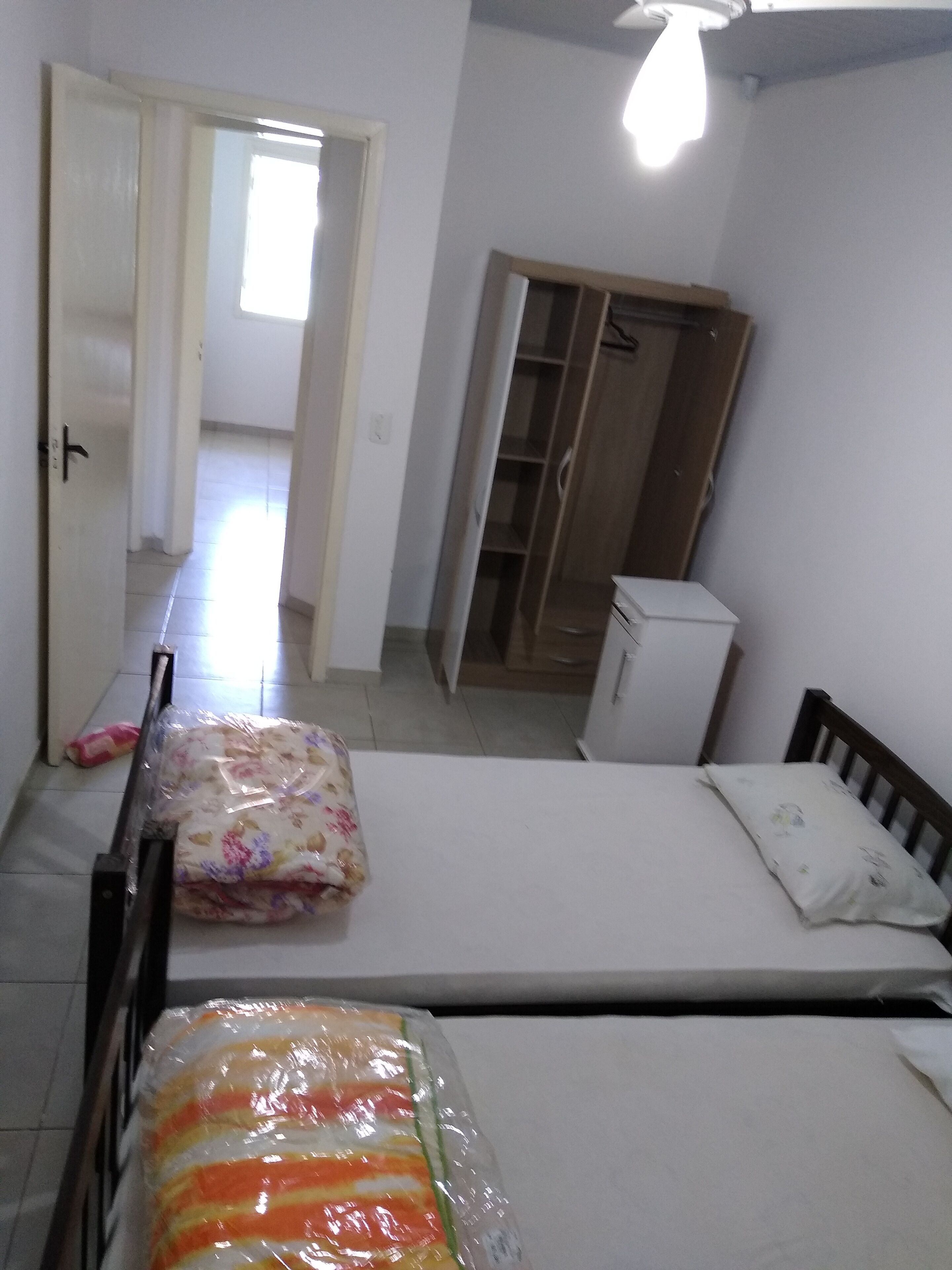 Une chambre avec deux lits, une armoire et un petit réfrigérateur.