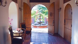 A corridor with wooden doors, a chair, a table, and a fountain in the background. - RedSmith Ranch (San Joaquin County)