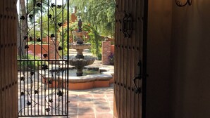 An arched doorway with a wrought iron gate leading to a courtyard with a fountain and a brick wall. - RedSmith Ranch (San Joaquin County)