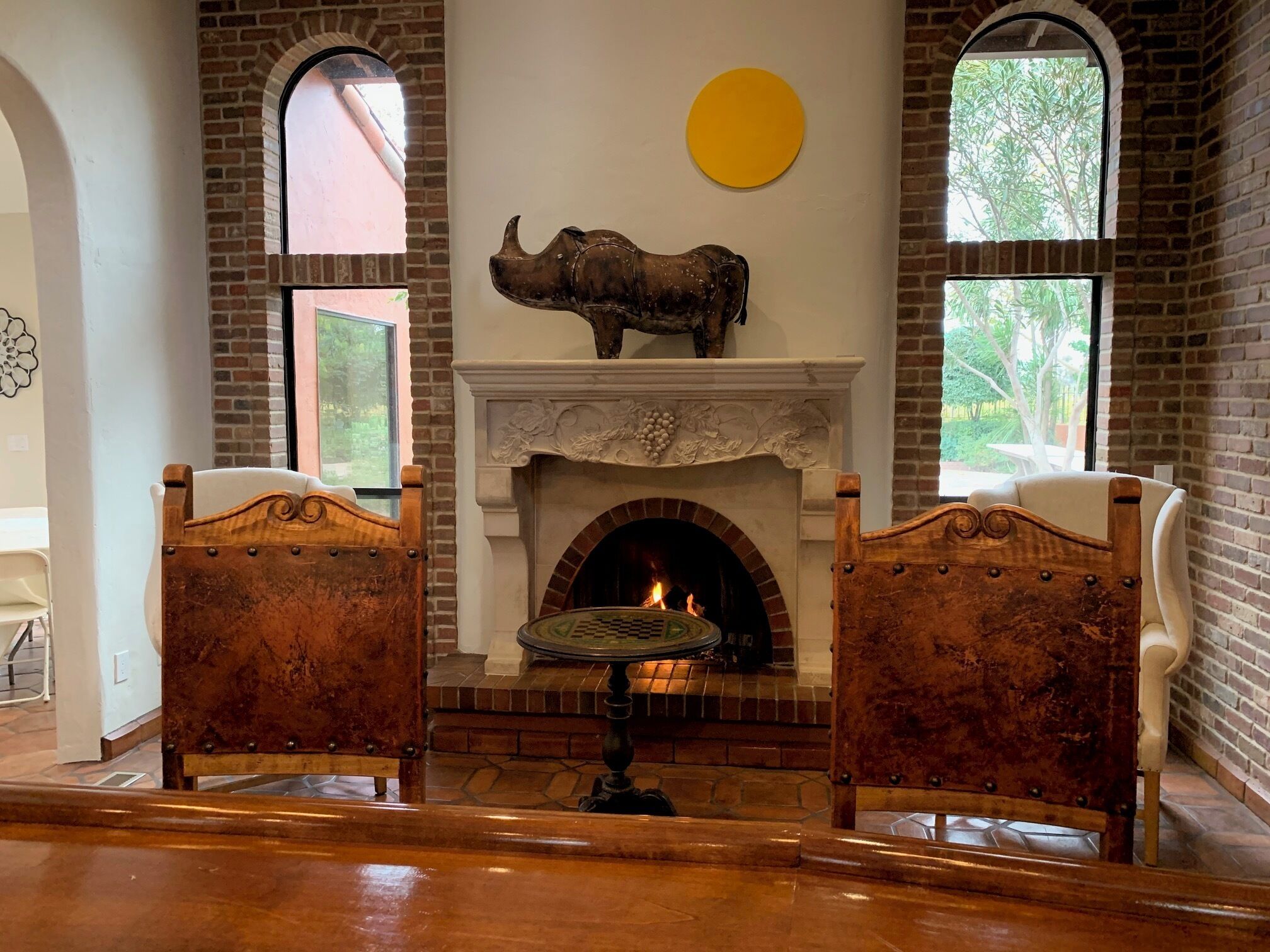 A room with a fireplace, two wooden chairs, and a round table.