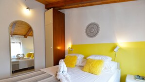 A hotel room with a bed, a mirror, a wall with a mandala design, and a yellow accent wall.