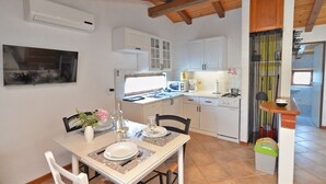 A compact kitchen with white cabinets, a microwave, a stove, and a dining area with a table set for two.