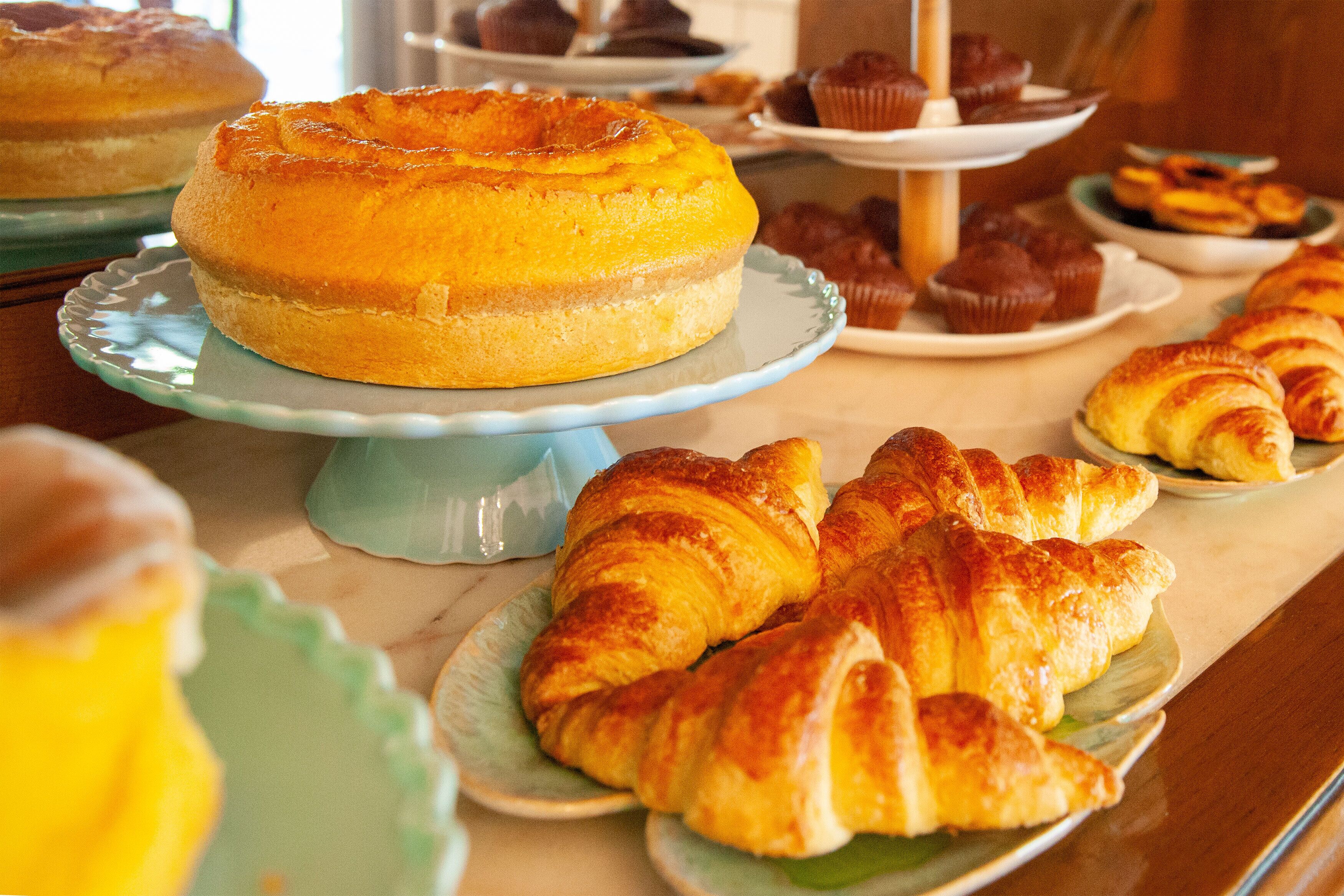 A buffet with various baked goods including a cake, muffins, and croissants.