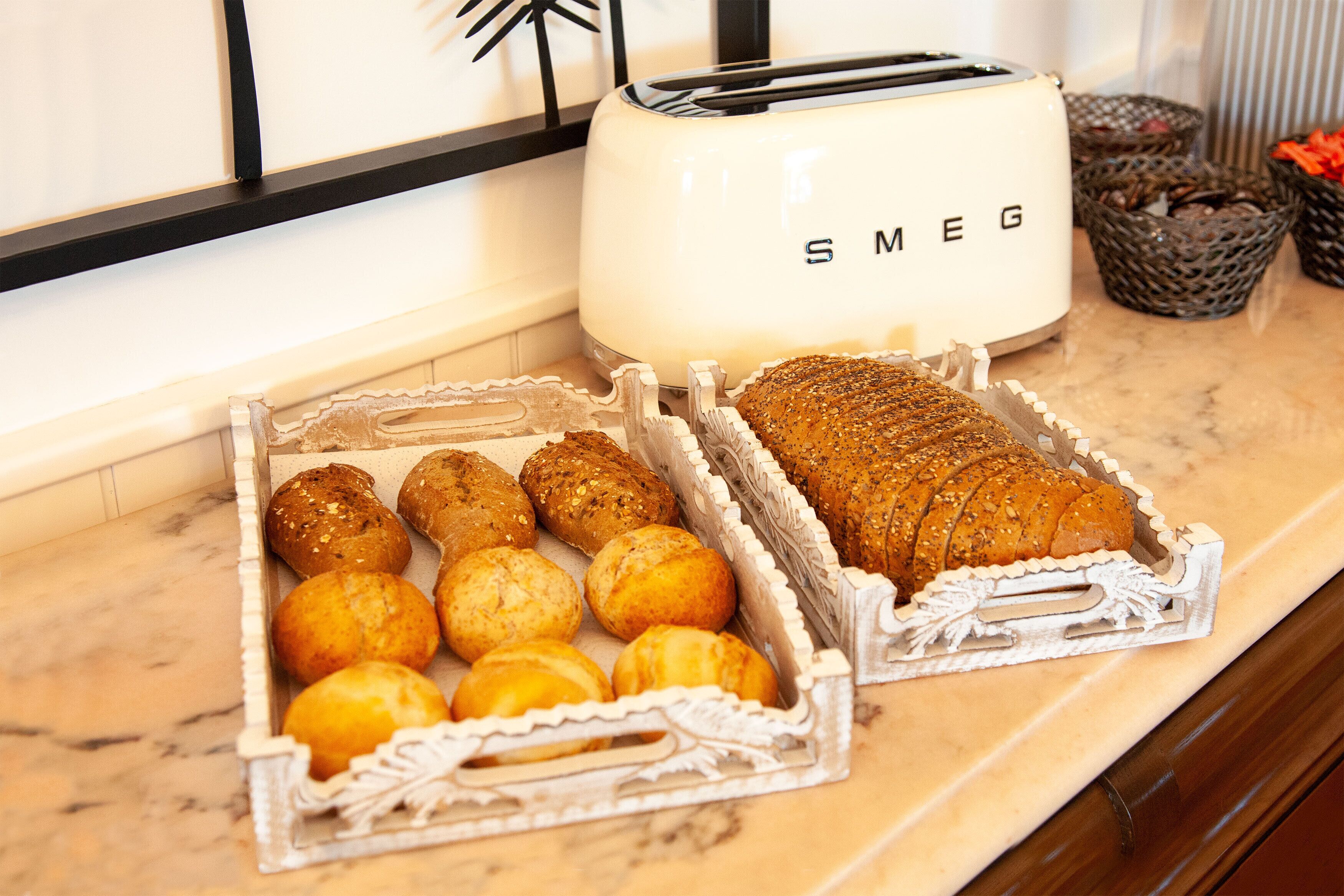 Uma bancada de cozinha com uma torradeira e bandejas de pão e pastelaria.