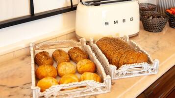Uma bancada de cozinha com uma torradeira e bandejas de pão e pastelaria.