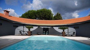 Una piscina con techo de azulejos, sillas de descanso y plantas en macetas.
