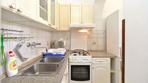 A compact kitchen with a double sink, a stove, and a built-in oven.