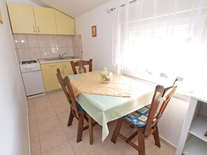 Enjoy meals in this cozy kitchen and dining area, featuring a gas stove, sink, and table for two.