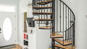 Una escalera de caracol con escalones de madera y barandillas de metal negro, que conduce a un piso superior.