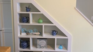 En vit hylla med dekorativa föremål och en skylt med texten ”BEACH HOUSE” ovanför.