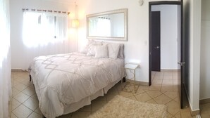 Une chambre à coucher avec un lit, une table de chevet, un miroir et une porte.