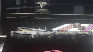 Een kamer met uitzicht op besneeuwde bergen, een raam met een metalen hekwerk en een tafel met een gestreepte tafelkleed en enkele items erop.