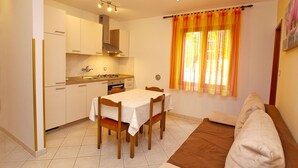 A compact kitchen with white cabinets, a dining table, and a sofa. - Apartment 1047/14848 (Istria - Rovinj), 1000m from the beach (Rovinj)