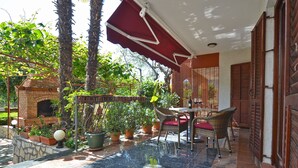 A covered patio with a brick oven, outdoor seating, and potted plants. - Apartment 1047/14848 (Istria - Rovinj), 1000m from the beach (Rovinj)
