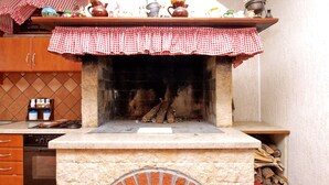 A kitchen with a brick oven, wooden cabinets, and a checkered cloth over the oven.