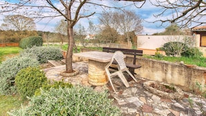 A patio area with a stone bench, a small table, and a tree. - Apartment 1049/3911 (Istria - Rovinj), 1300m from the beach (Rovinj)