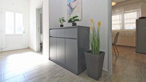 A hallway with a grey cabinet, a painting of a boat, and potted plants. - Apartment 1052/3918 (Istria - Fažana), 300m from the beach (Fažana)