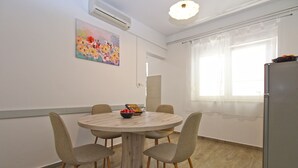 A dining area with a round table, four chairs, a bowl of fruit, and a painting on the wall. - Apartment 1052/3918 (Istria - Fažana), 300m from the beach (Fažana)