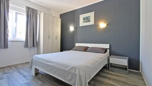 A bedroom with a bed, a nightstand, a wardrobe, and a picture on the wall. - Apartment 1052/3918 (Istria - Fažana), 300m from the beach (Fažana)