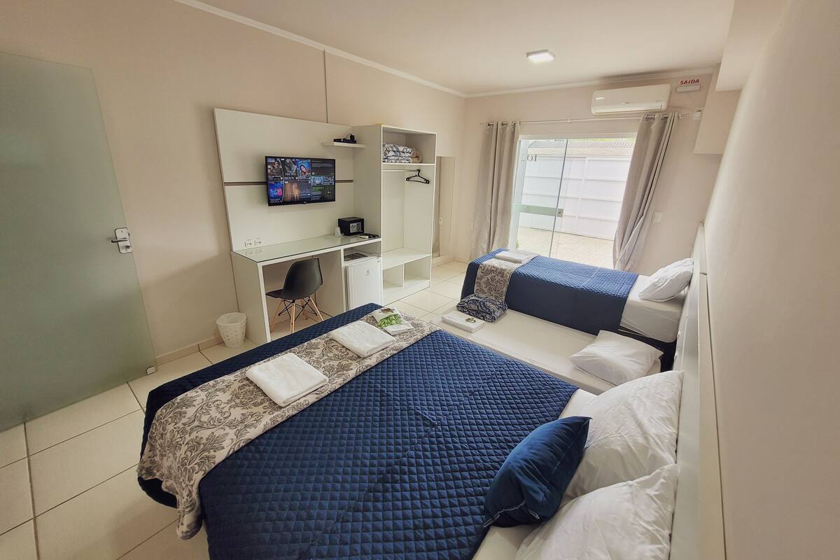 Une chambre d’hôtel avec deux lits, une télévision, un bureau et un balcon.