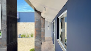 A modern building with a covered walkway, stone pillars, and large windows. - Pousada Amanhecer do Sul (Penha)