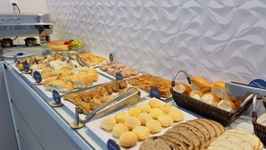 A buffet with various food items including pastries, bread, and a selection of fruits. - Pousada Amanhecer do Sul (Penha)