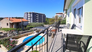 A balcony with a pool, a stone wall, and a view of surrounding buildings. - Apartment 1056/4401 (Istria - Pula), 500m from the beach (Pula)