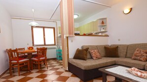 Un salon avec un sol à carreaux, un canapé, une table basse et une table à manger avec des chaises.