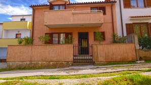 Une maison à deux étages avec un balcon, une porte d’entrée et un petit porche.