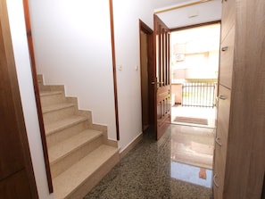 Stairs lead to an upper floor in this well-maintained space with a door to an outdoor area.