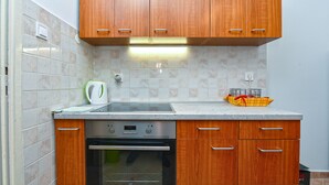 A kitchen with wooden cabinets, a built-in oven, a dishwasher, and a tiled backsplash. - Apartment 1066/5084 (Istria - Rovinj), 1000m from the beach (Rovinj)