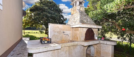 A stone structure with a statue on top, a small door, and a tiled floor.