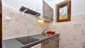 Uma cozinha compacta com forno embutido, pia e janela acima da pia.