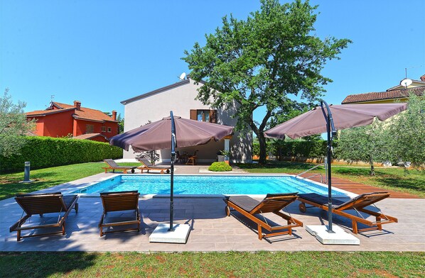 Relax by the serene pool surrounded by lounge chairs and lush greenery.