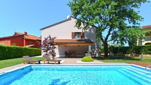 A swimming pool with lounge chairs, a covered patio, and a house with a tiled roof. - Apartment 1089/9537 (Istria - Poreč), 2000m from the beach (Poreč)