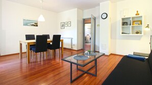 Un salon moderne comprenant un coin repas, un plancher en bois et une table basse en verre.