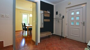 Une pièce comprenant un coin repas, un porte-manteau et une porte dotée de panneaux en verre dépoli.