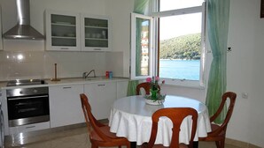 A kitchen with white cabinets, a stainless steel range hood, and a window with green curtains. - Apartment 1093/9443 (Istria - Rabac), 100m from the beach (Rabac)