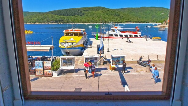 A harbor with boats, a souvenir shop, and a green hillside in the background. - Apartment 1093/9443 (Istria - Rabac), 100m from the beach (Rabac)