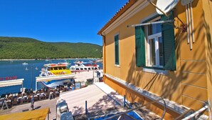 A coastal building with a satellite dish, a staircase leading to a terrace, and a view of boats on the water. - Apartment 1093/9443 (Istria - Rabac), 100m from the beach (Rabac)
