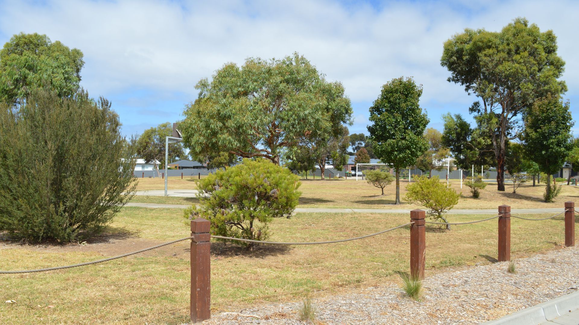 A park with various trees and a fenced area.