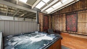 A hot tub area with a wooden deck, bamboo wall panels, and a ceiling with skylights.