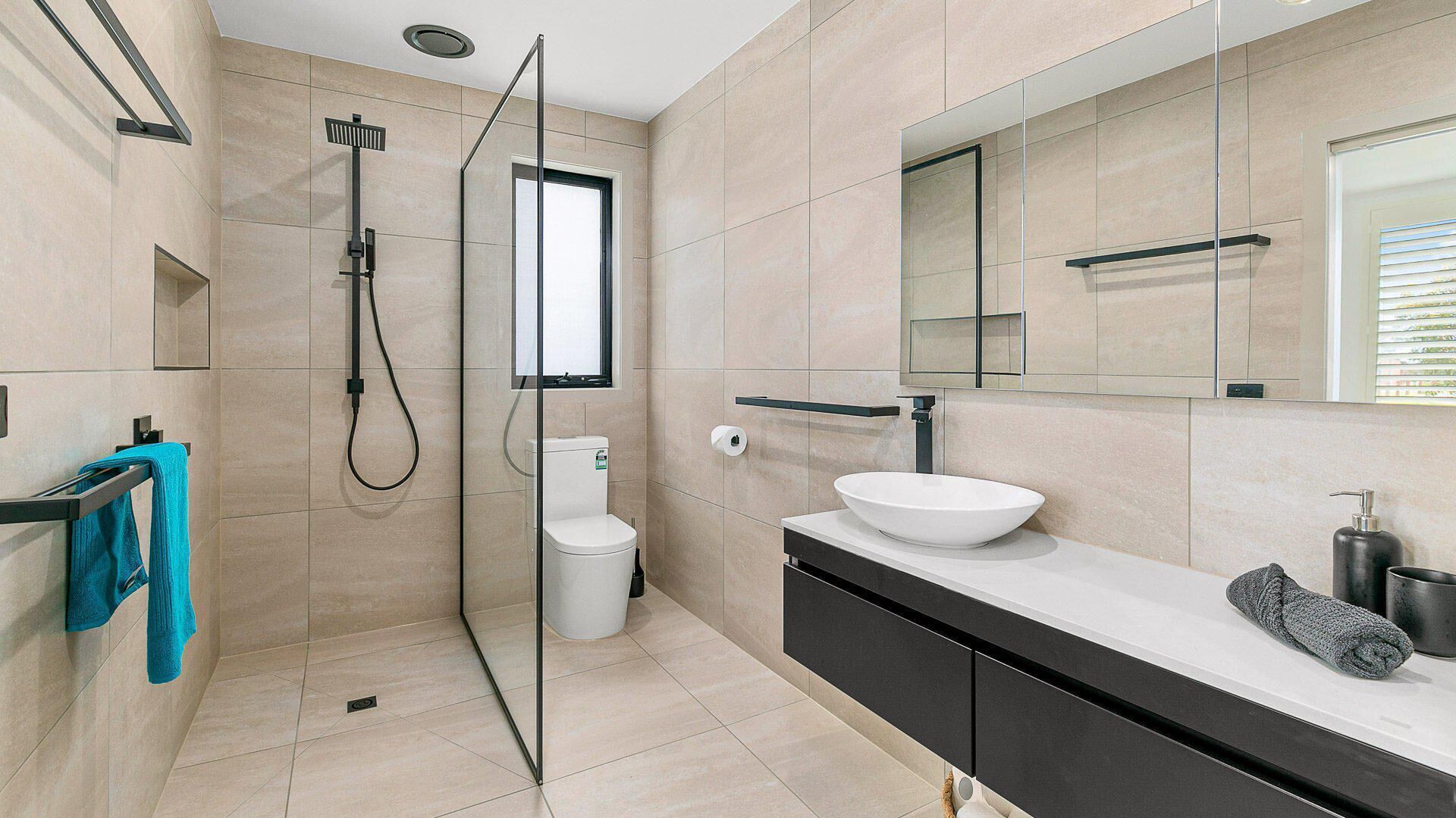 A modern bathroom with a glass shower enclosure, a white sink, and a large mirror.