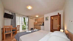 A hotel room with a bed, a desk, a chair, a TV, a kitchenette, and a bathroom. - Apartment 1099/9466 (Istria - Rovinj), 400m from the beach (Rovinj)