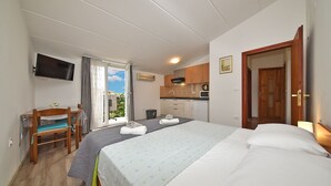 A bedroom with a bed, a desk, a chair, a television, and a kitchenette. - Apartment 1099/9467 (Istria - Rovinj), 400m from the beach (Rovinj)