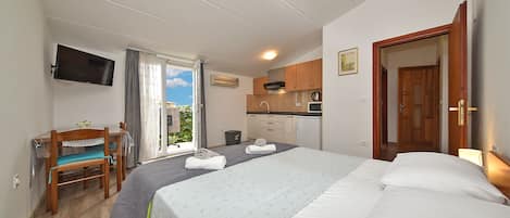 Une chambre comprenant un lit, un bureau, une chaise, un téléviseur et un coin cuisine.
