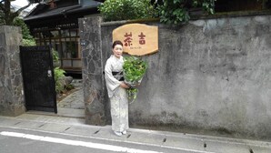 En person som står framför en byggnad med en stenmur och en skylt med japanska tecken.